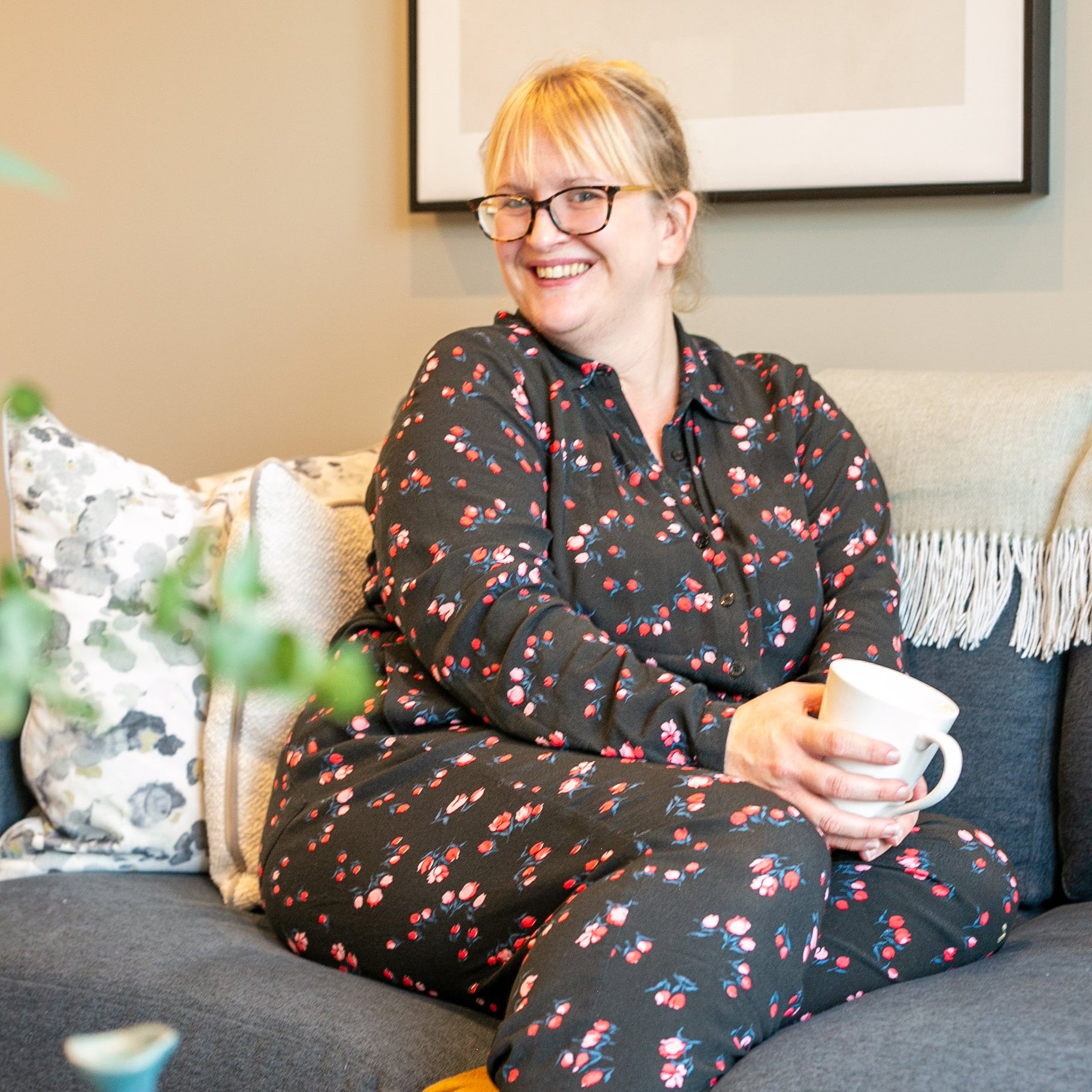 A woman sitting on a sofa with a cup of tea