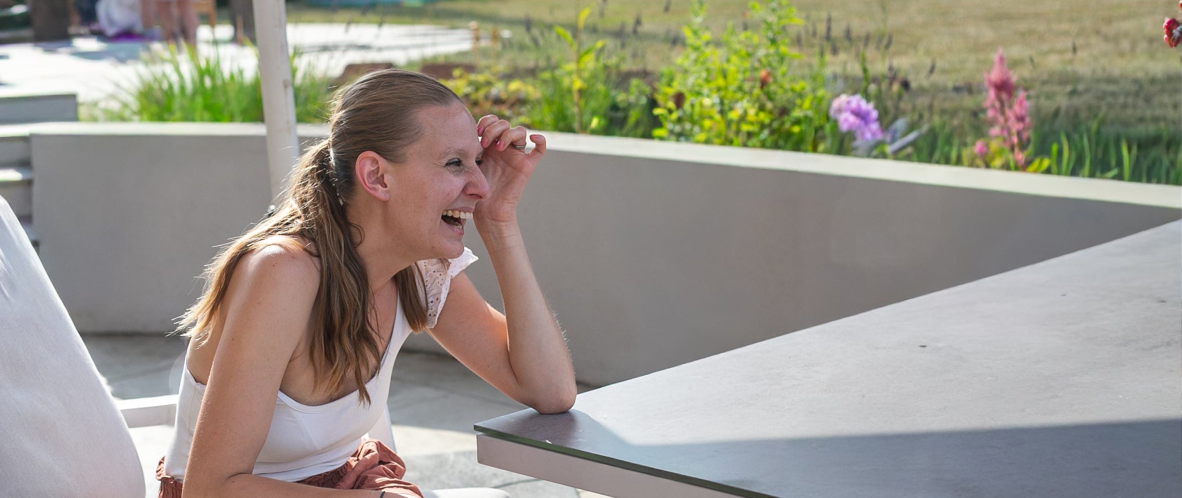 Woman sitting at a table outdoors laughing